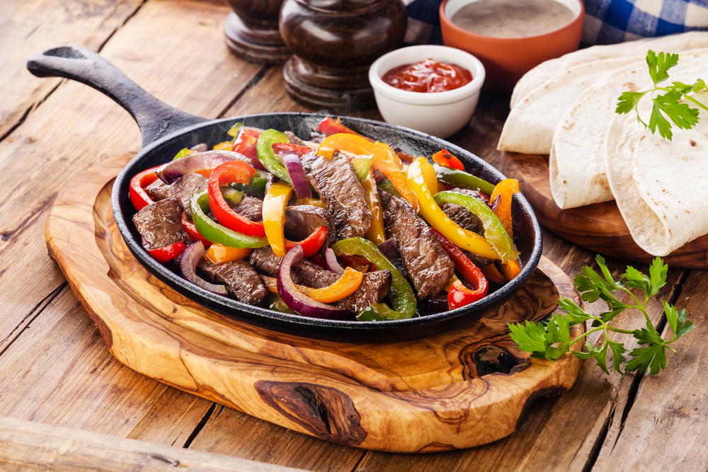 Steak fajitas and vegetables served on a table.