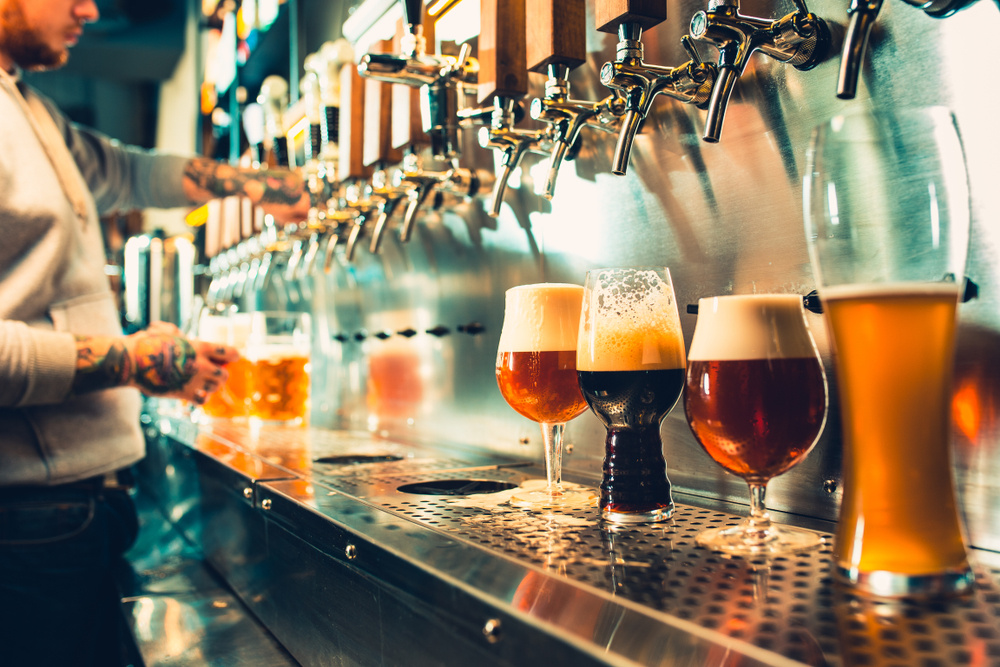 A large area where there are a lot of taps in a bar. On the space under where the beer taps are there are glasses of different shapes full of beer of different colors. A great restaurant in Tupelo. 