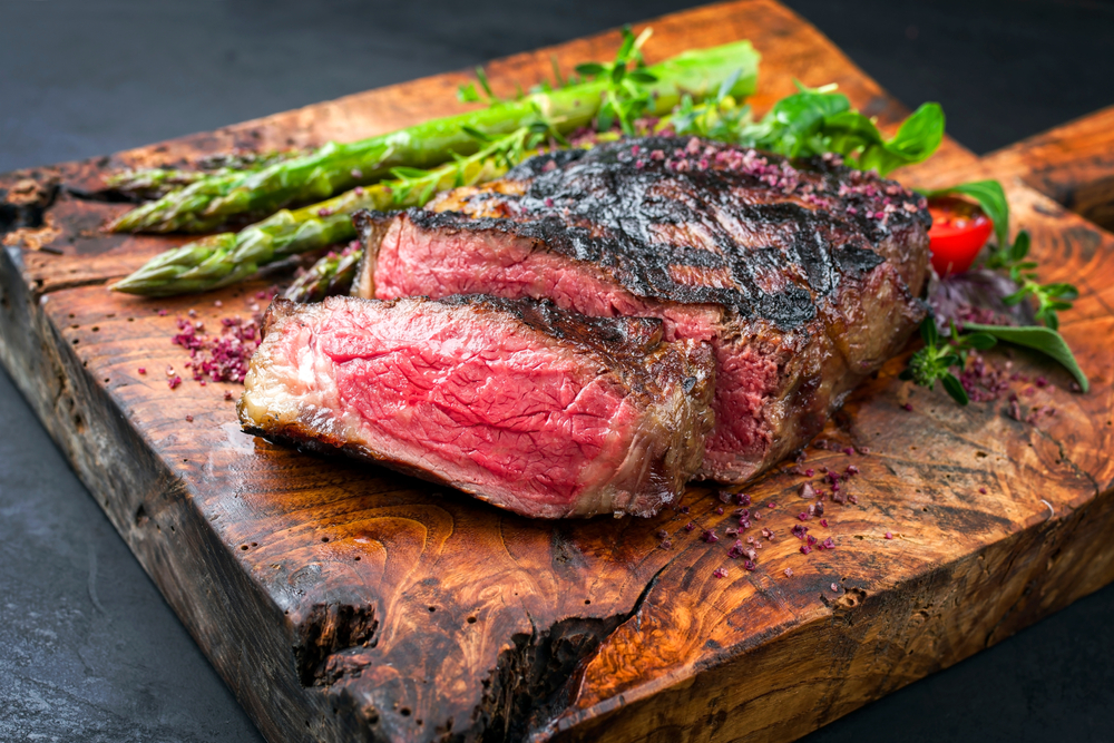 wagyu steak on a wooden chop block with asparagus 