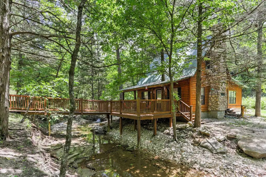 log cabin and wooden bridge in front of the cabin in the woods, stone chimney