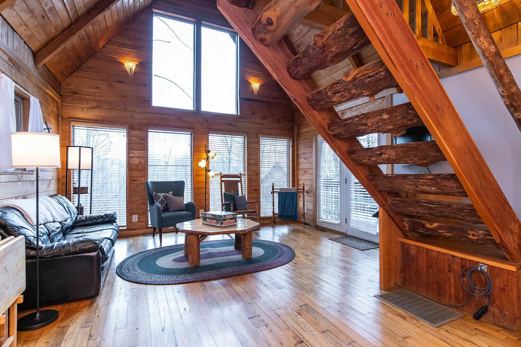 inside a cabin in kentucky with couch, chairs, and wooden details