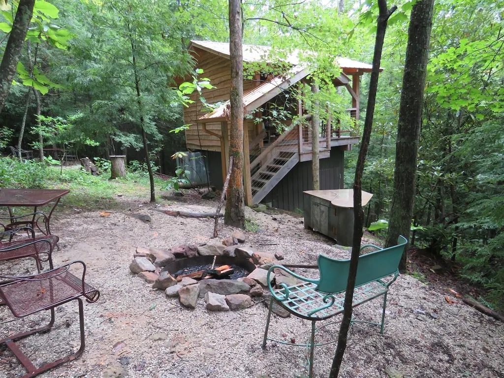 small elevated cabin with fire pit and chairs outside