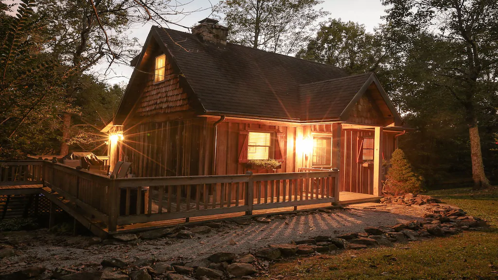 cabin with lights on and wrap around porch
