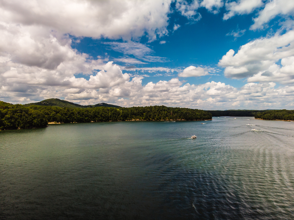 An aerial view of small boats passing by a small swimming beach during a sunny day on Lake Altoona, one of the beaches near Atlanta.