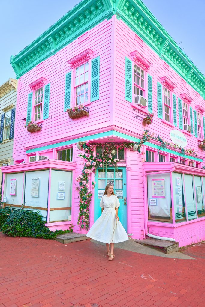 Girl in a white dress standing in front of the brightly colored Call Your Mother deli.
