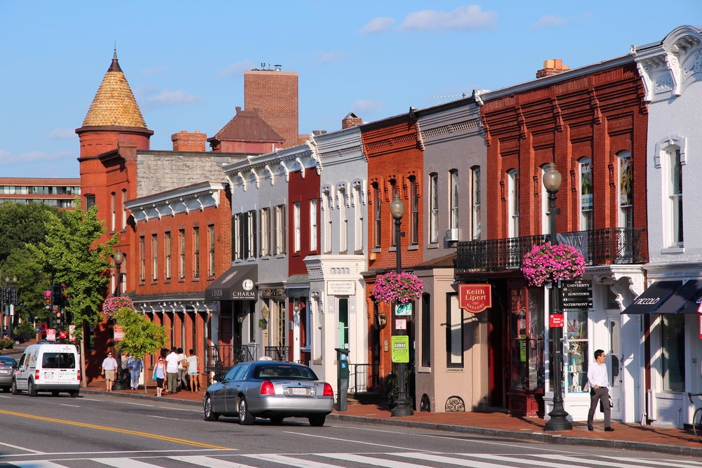 A line of cute shops in Georgetown with people walking on the sidewalk.