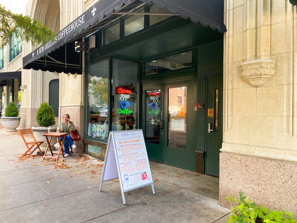 The outside of the New Orleans Coffeehouse in Asheville with a black awing and some seats outside