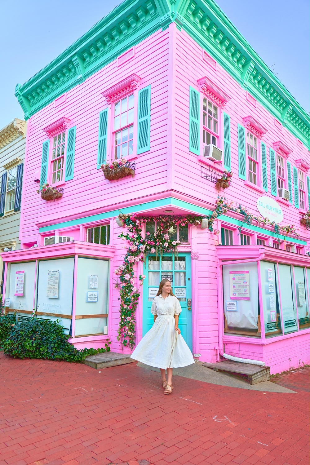 A woman in a white dress standing in front of a historic bright pink building in Georgetown. The building has bright blue trim. Georgetown is one of the best things to do in Washington DC.