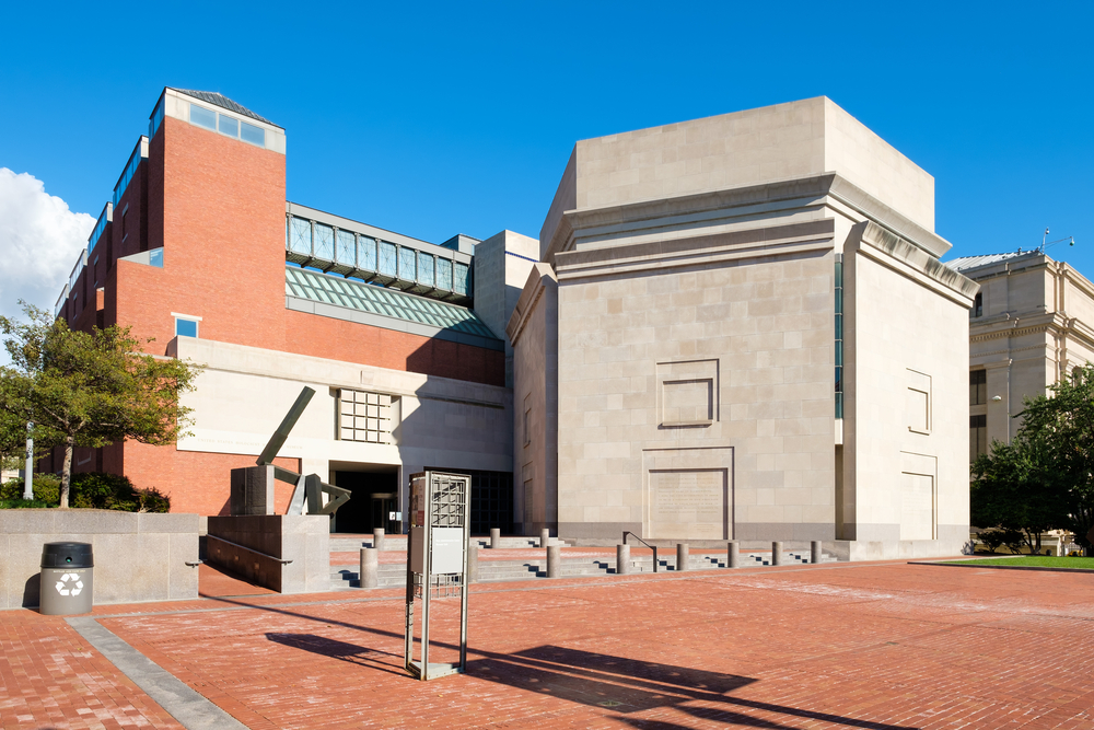 The exterior of the National Holocaust Memorial Museum. It is a brick and stone building with different levels and sections. In front of it is a brick courtyard. 