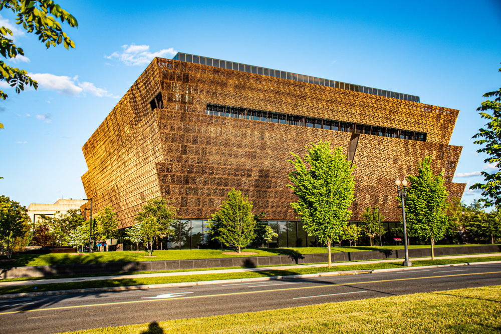 The exterior of the National Museum of African American History and Culture in Washington DC. It is an interesting angular building that appears to be made of shiny copper. 