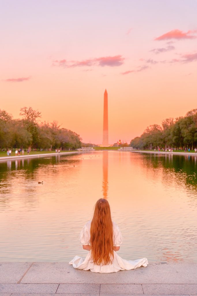woman sitting in washington DC during sunset she is wearing a white dress