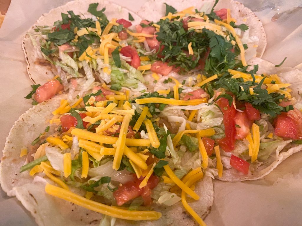 Four tacos on a plate with tomatoes, lettuce, cheese and cilantro at on of the Mexican restaurants in Blowing Rock