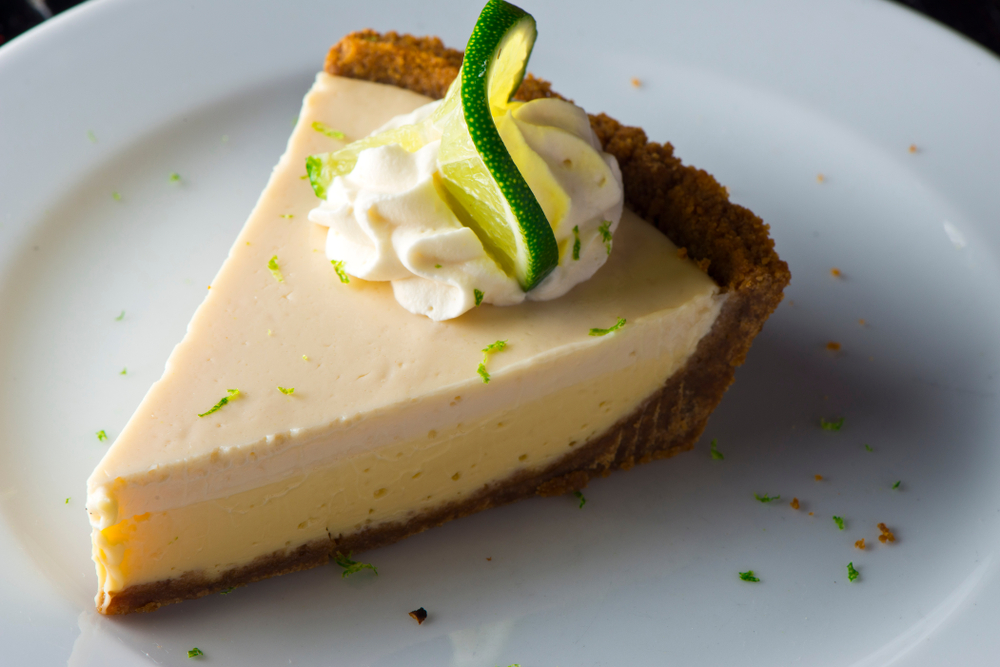 a slice of key lime pie on a plate with whipped cream and a lime slice