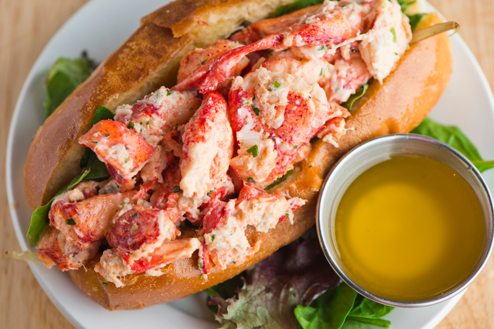 a lobster roll with a little cup of butter on a plate from Sea Shack, one of the best restaurant in Hilton Head