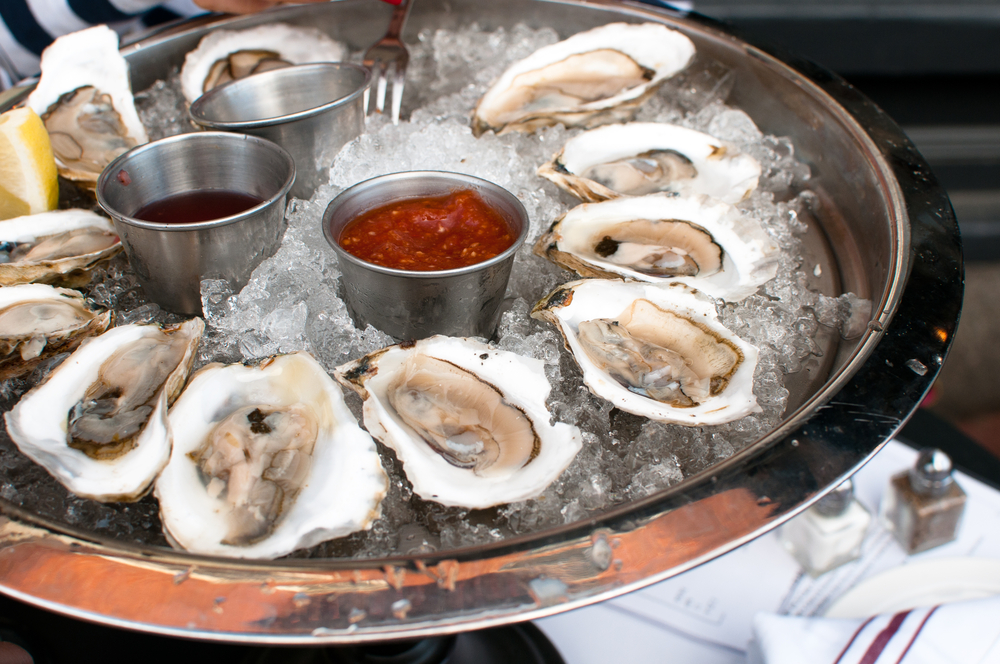 oysters on the half shell on ice with lemon slice and sauces