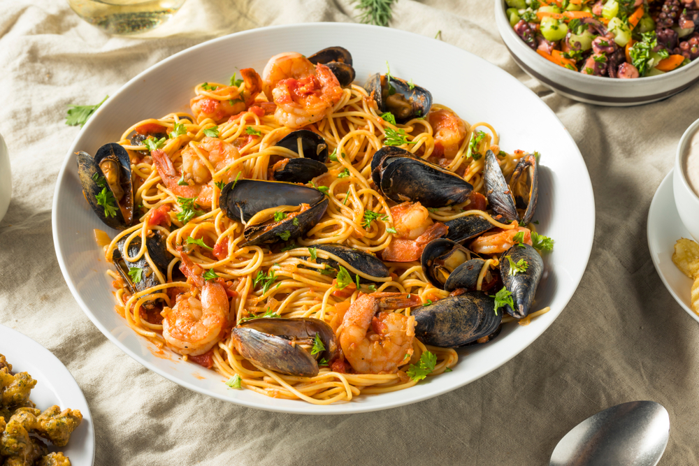 seafood pasta in a bowl surrounded by other bowls and plates on a table