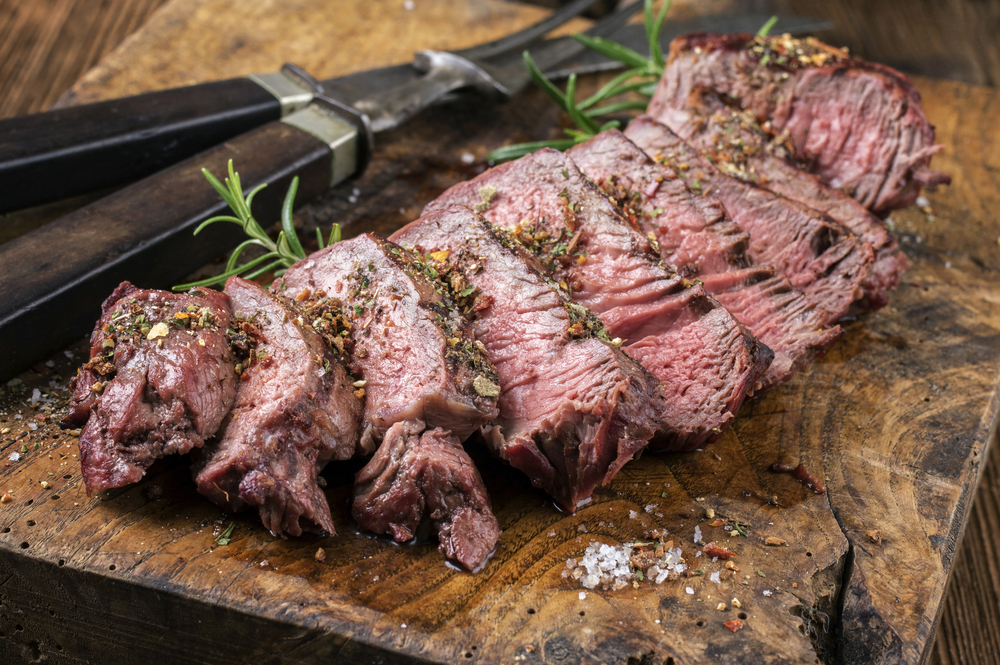 steak au poivre on a wooden board with steak knife