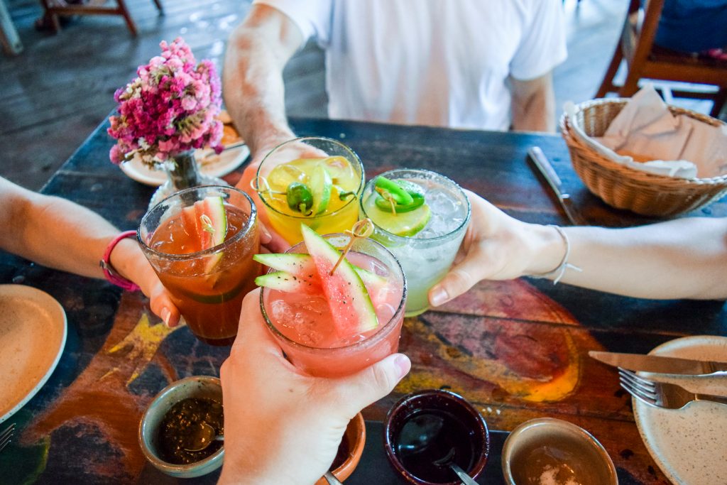people clinking alcoholic drinks together at a table