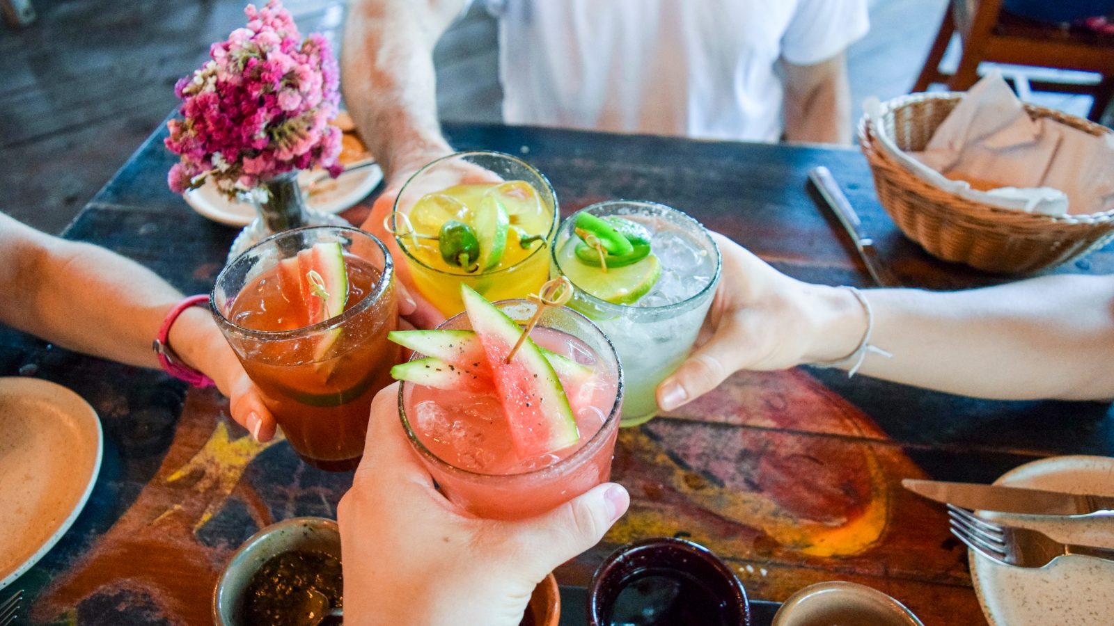 people clinking alcoholic drinks together at a table