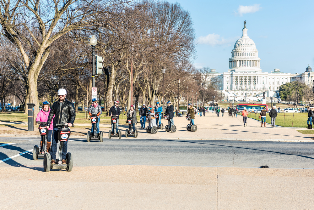 A group of people riding segways in Washington DC. In the background you can see the US Capitol Building. 