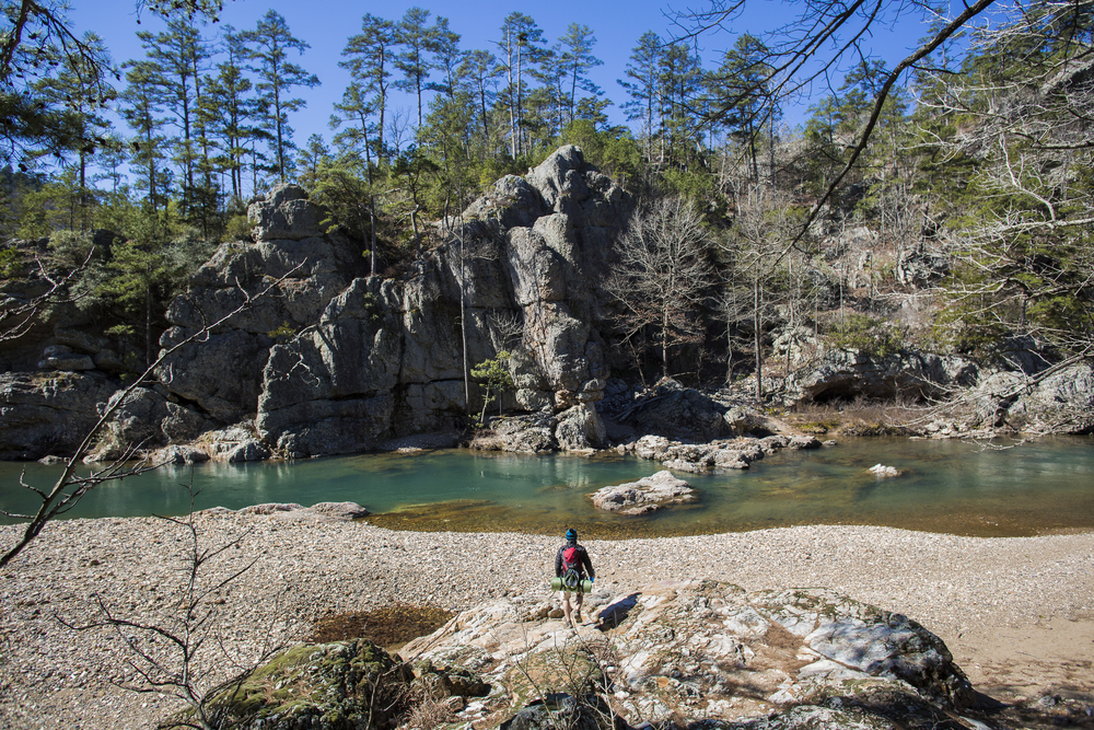 a large rock formation in ouachita national forest with a hiker in front