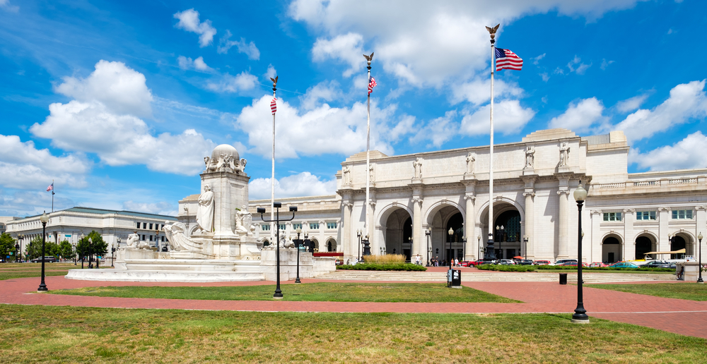 The exterior of Union Station in Washington DC, one of the best ways to get to the city for a weekend in Washington DC. It is an old stone building with a large elaborate fountain in front of it. 
