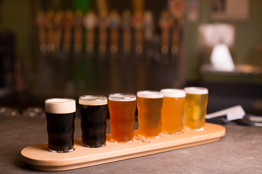 A flight of craft beers in different colors on a bar top.