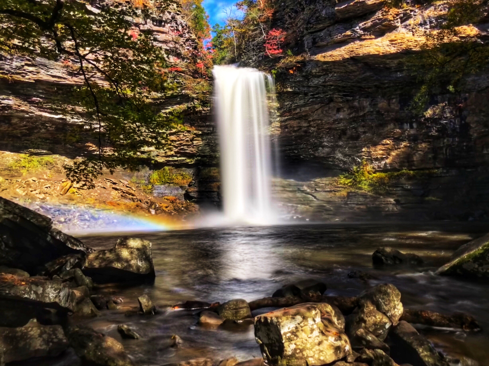 Beautiful Cedar Falls with a small rainbow .