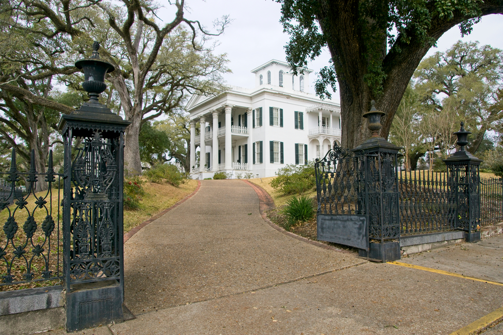 The white, columned Stanton Hall in Natchez looking regal surrounded by trees.