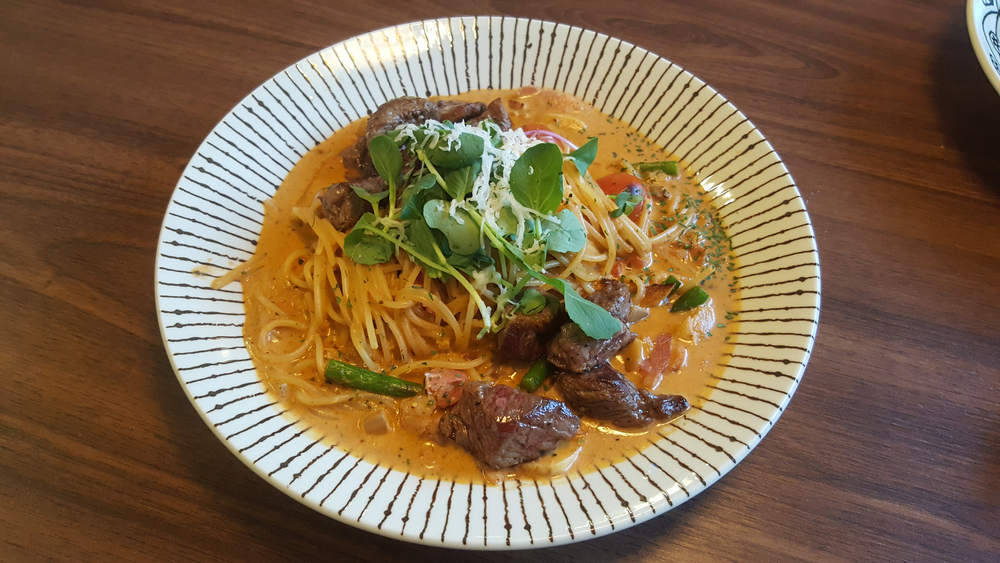 Spaghetti pasta with pieces of sirloin steak, topped with greens as a garnish, similar to the signature dish at Cafe Portofino, one of the best Italian restaurants in Boone, NC.