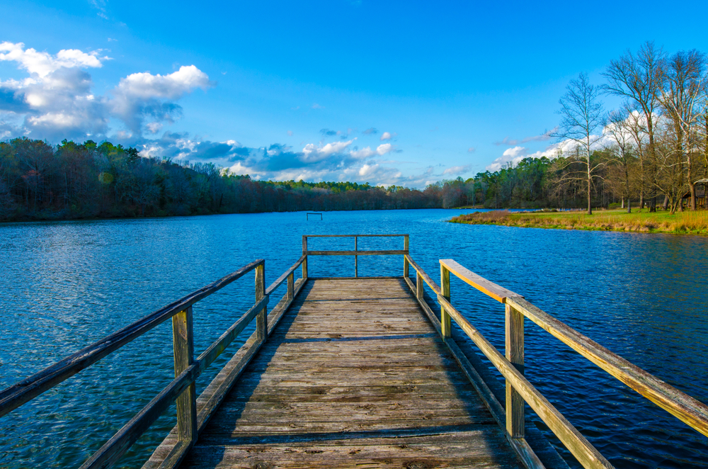 A pier going into a blue lake on a sunny day.