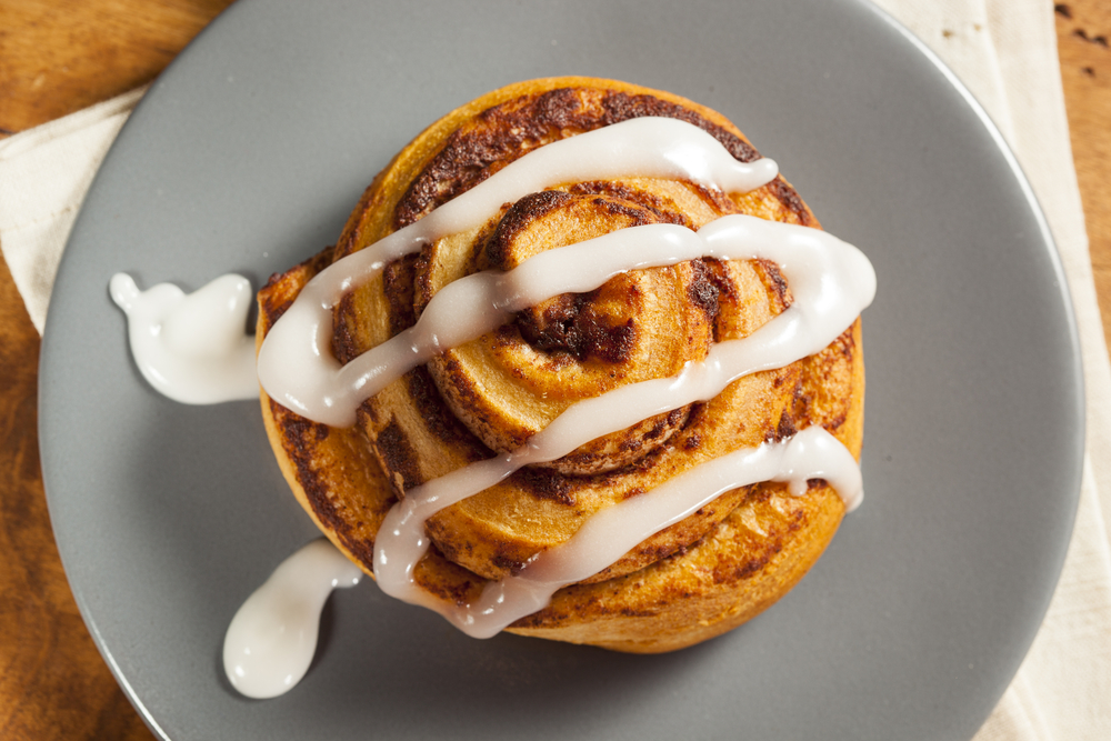 a cinnamon roll with icing  on a gray plate