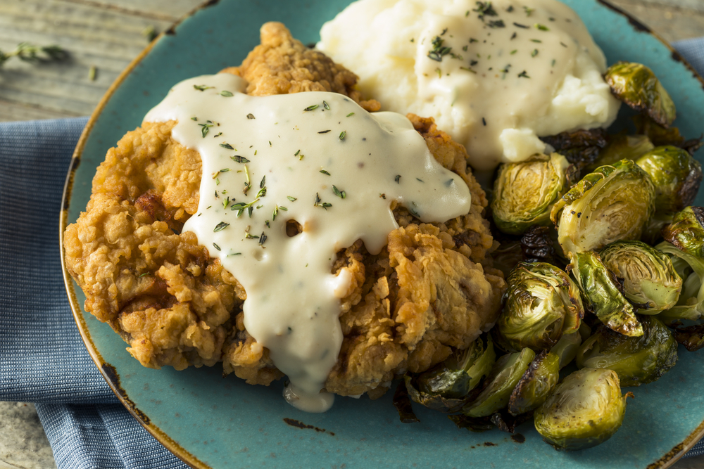 country fried steak with sprouts and mashed potatoes on a blue plate