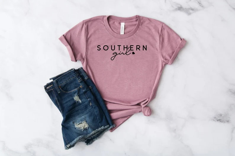 pink shirt with short sleeves and pair of distressed denim shorts on marble back ground for southern gifts