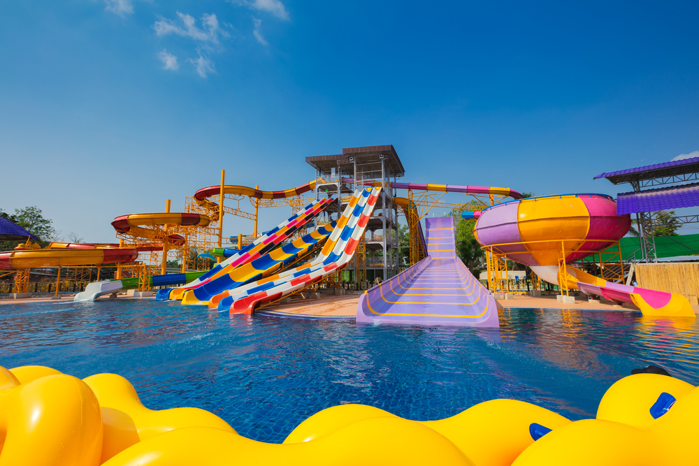 A set of waterslides at a water park like the ones you can find that are one of the most fun things to do in Gulf Shores. They are different colors, stripped, and lead to a large pool. 