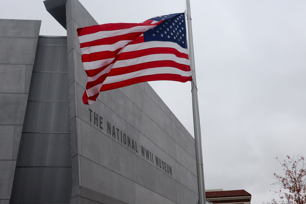 An American flag flies outside of the smooth, modern exterior of the National WWII Museum in New Orleans.