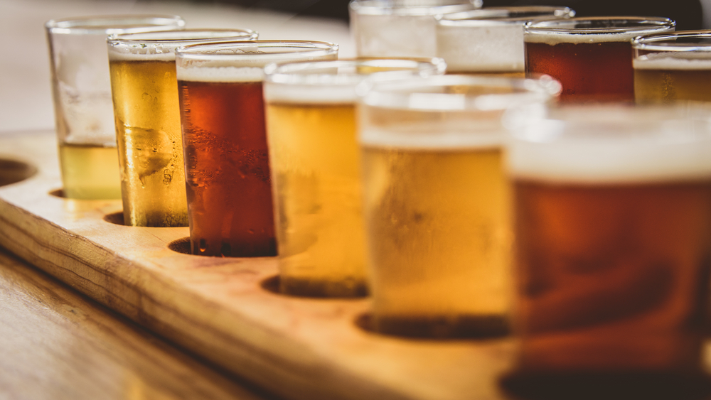 A flight of different types of craft beers in a wooden tray.