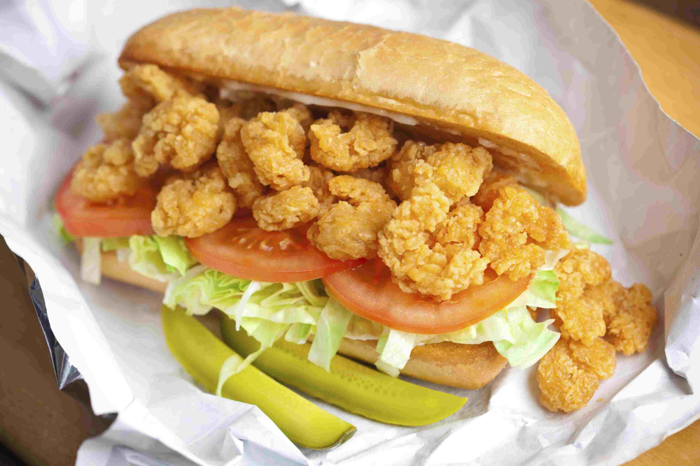 A po-boy sandwich with fried shrimp, tomatos, and lettuce, similar to the dish served at Li'l Dizzy's restaurant in New Orleans.