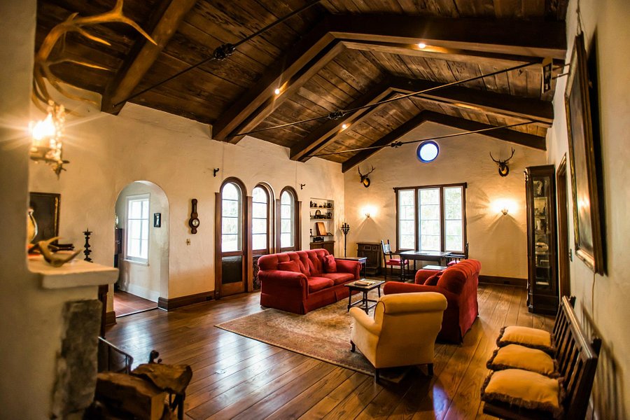 The rustic yet intimate lodge with red couches, a wood ceiling and antlers