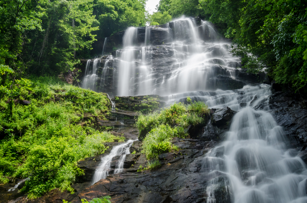 The Amicola falls surrounded by large rock facade and greens shrubs