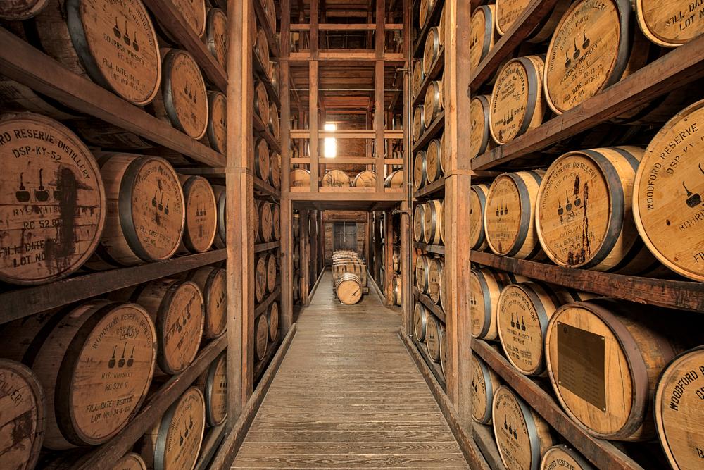 wood barrels of bourbon stacked on shelves at distillery 