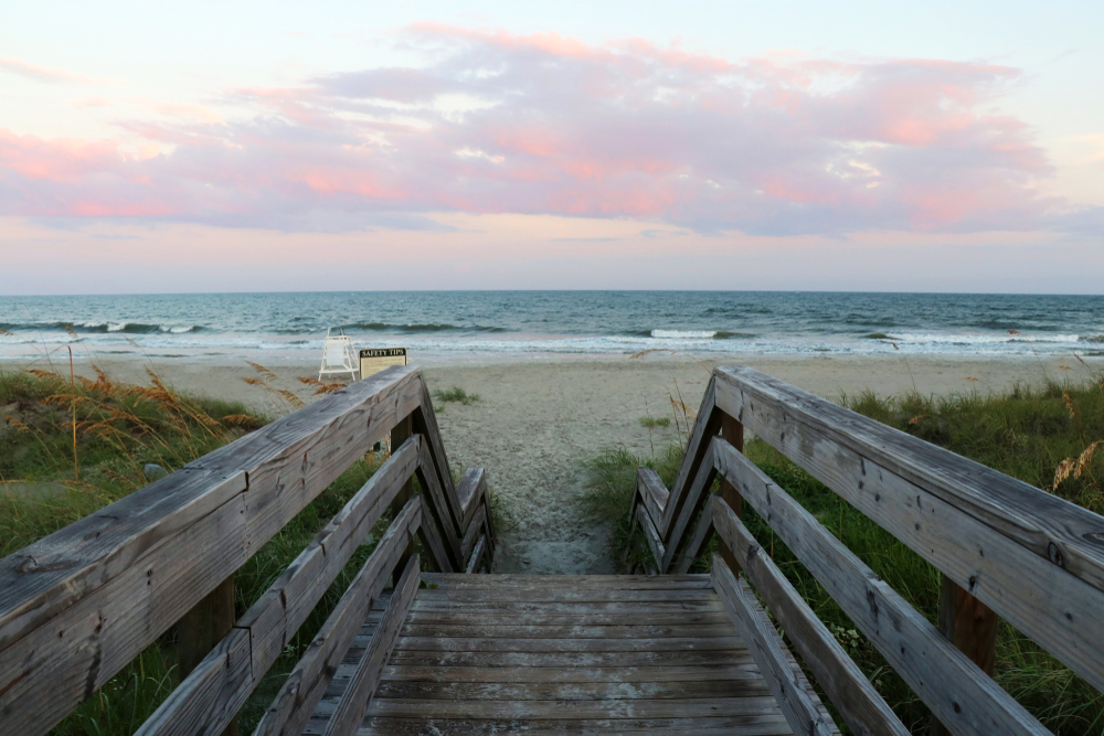 wooden steps down to beach with blue and pink sky