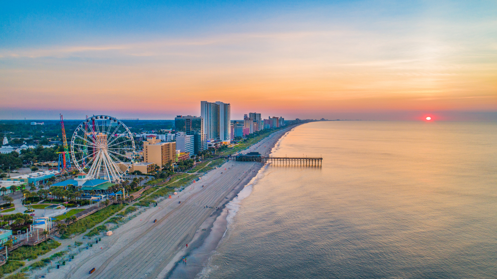 aerial view beach, resorts, ocean and ferris wheel at sunset