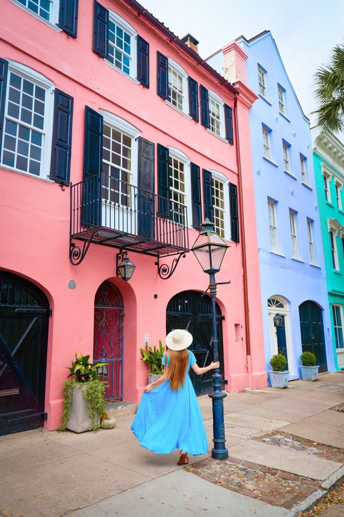 woman in blue dress near lamppost in front of colorful row houses