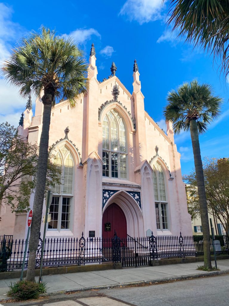 The beautiful front of the French Huguenot Church with palm trees.