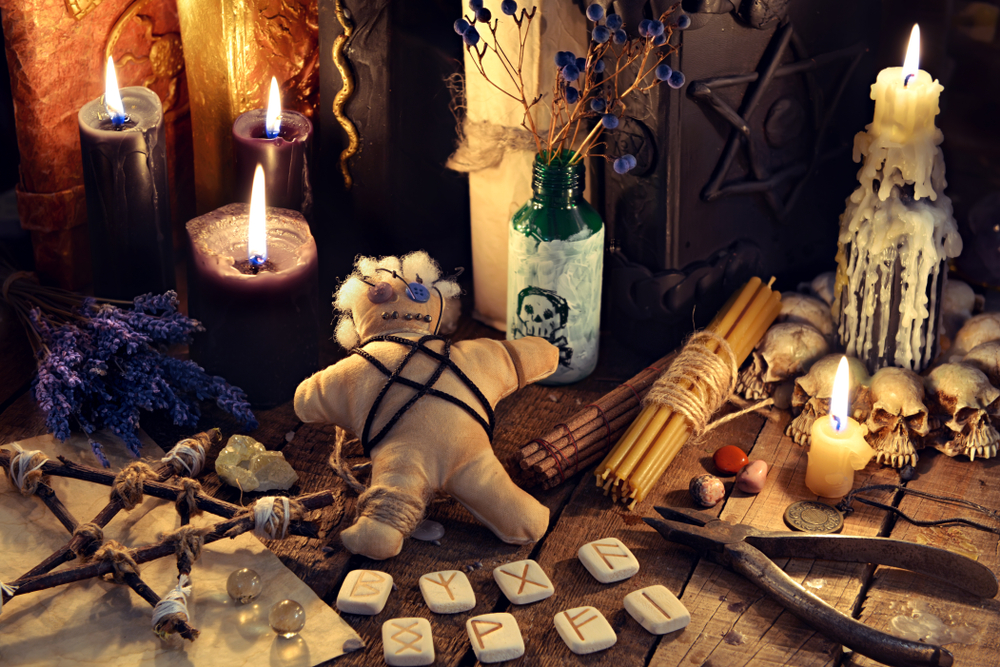 A Voodoo altar set up with a voodoo doll, candles, runes, and other items. 