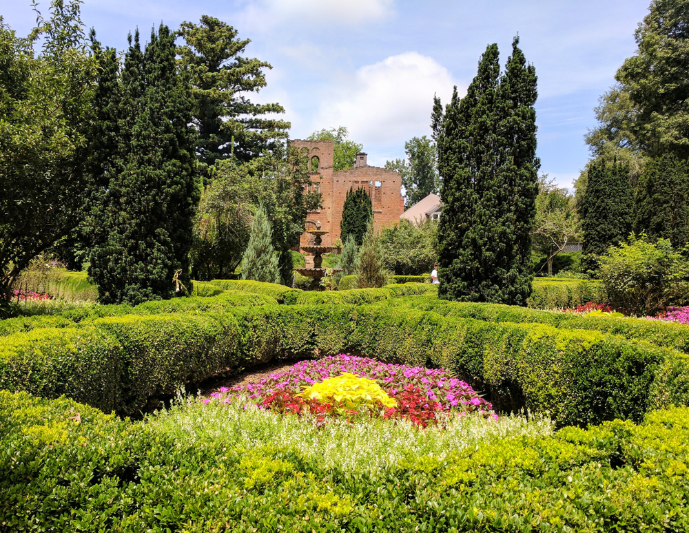 A formal garden with an italian style ruin in the background 