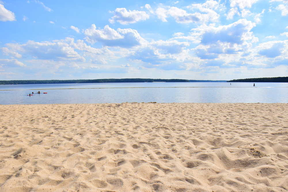 wide sandy beach with a swimming area in the lake