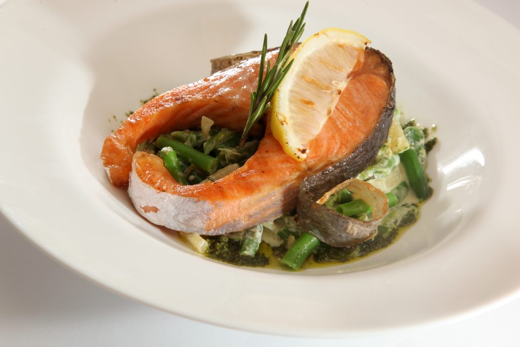 Salmon on top of green vegatables on a plate in an article about resturants in Knoxville 