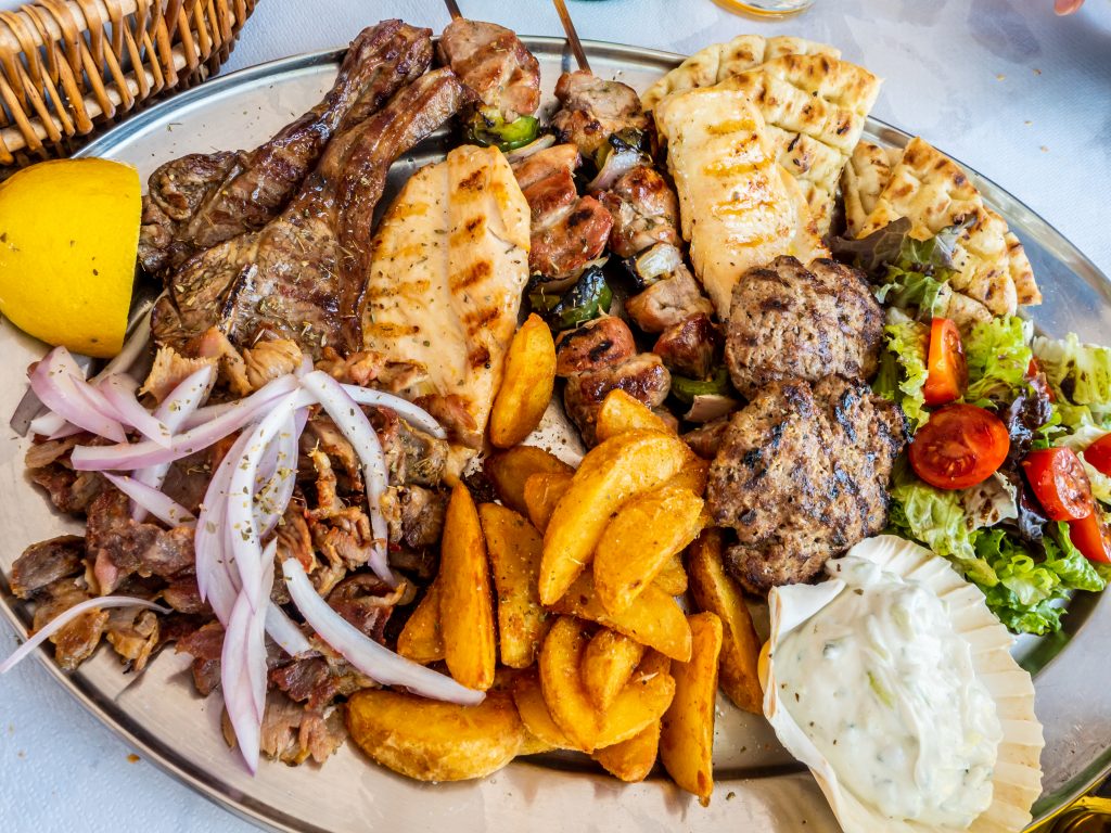 Various meats on a plate with freis and a side salad